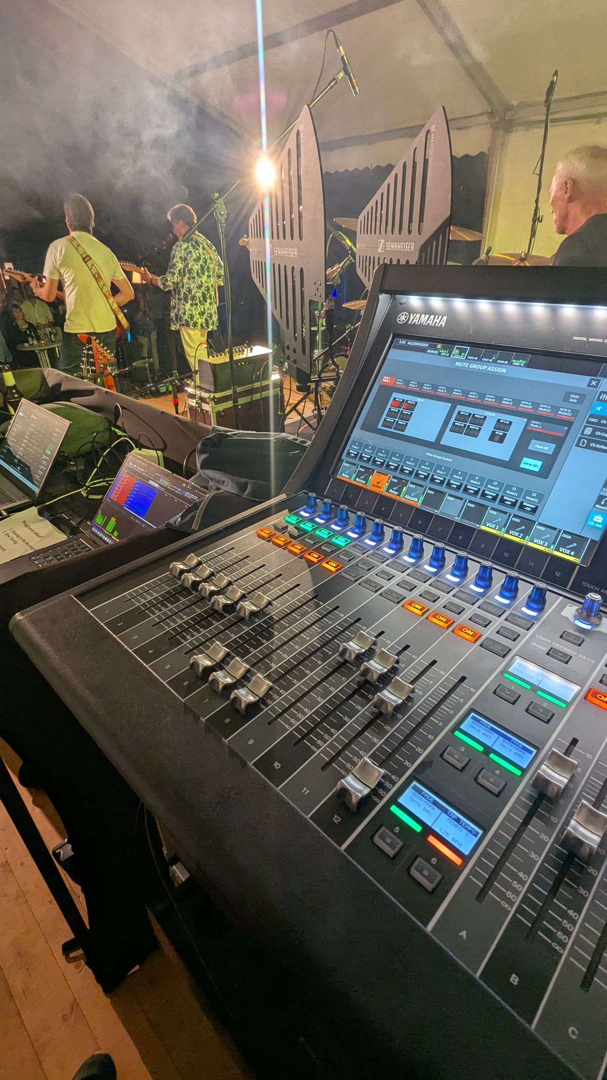 Mischpult mit Live-Band auf der Bühne im Hintergrund