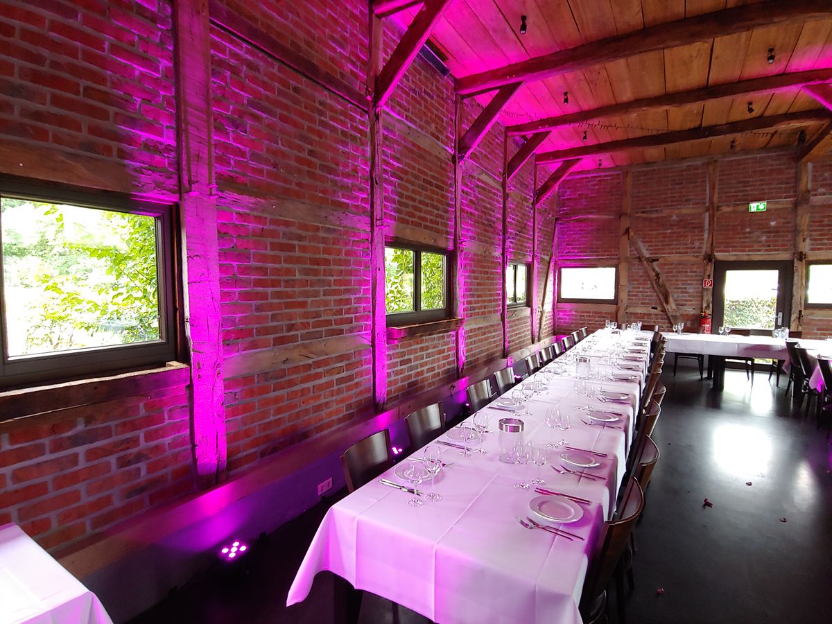 Backstein-Location mit eingedeckten Tischen und pink-violettem Uplight