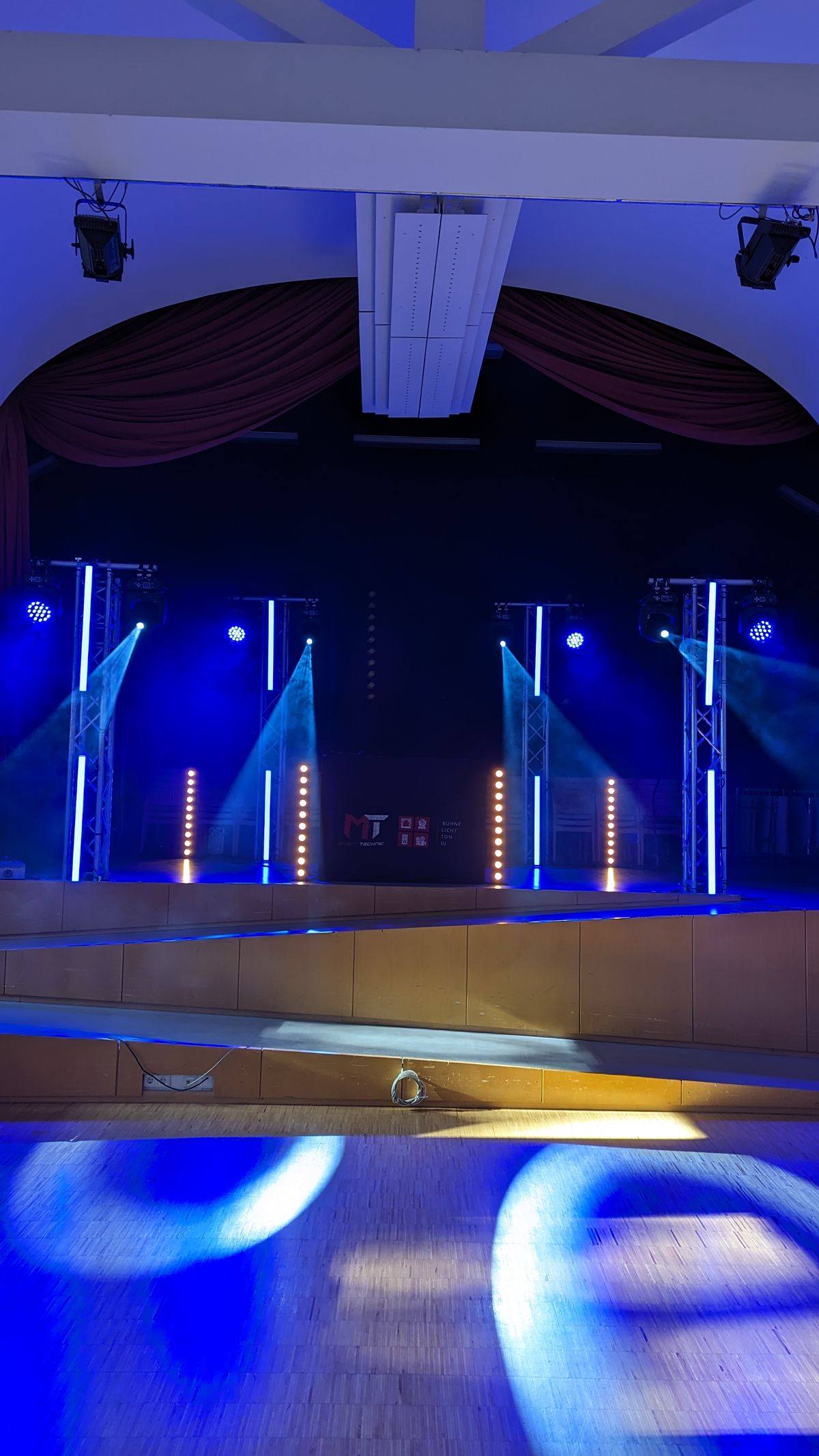 Saal mit blauer LED-Bar-Beleuchtung und Bühne